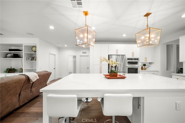 kitchen with stainless steel appliances, visible vents, a kitchen island, and white cabinetry