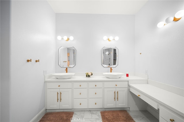 bathroom with marble finish floor, double vanity, a sink, and baseboards