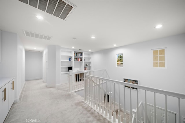 hall with light colored carpet, visible vents, an upstairs landing, and recessed lighting