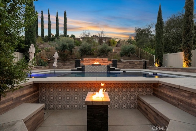 view of patio with a fenced in pool, a fenced backyard, and a fire pit