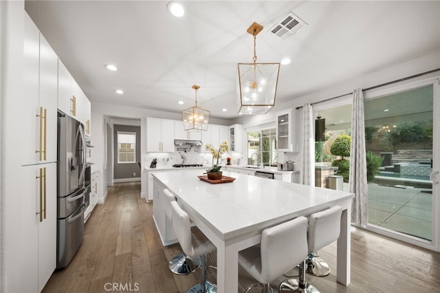 kitchen with stainless steel appliances, wood-type flooring, visible vents, and a healthy amount of sunlight