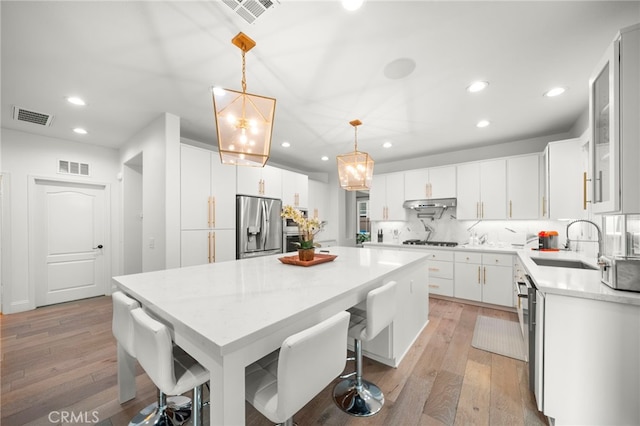 kitchen with under cabinet range hood, visible vents, appliances with stainless steel finishes, and a sink