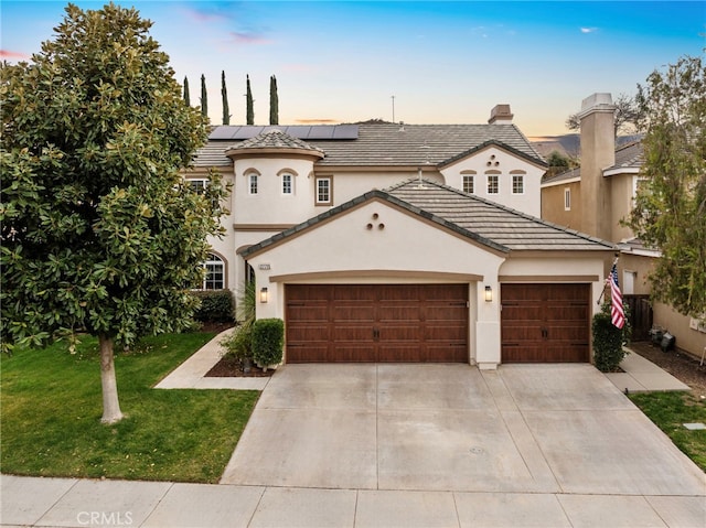 view of front of home featuring stucco siding, solar panels, concrete driveway, an attached garage, and a front lawn