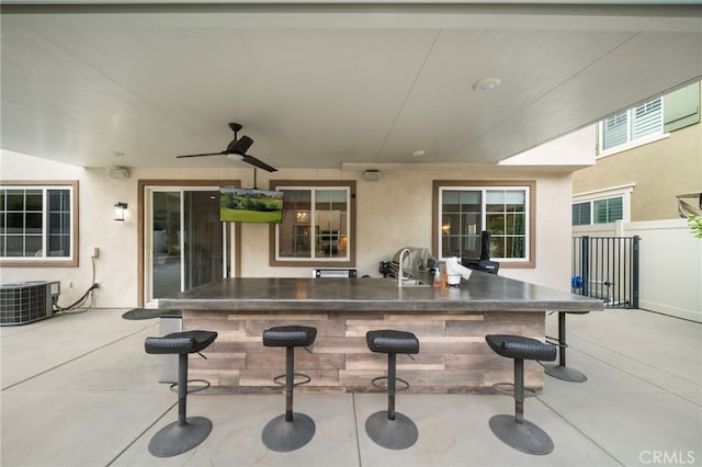 view of patio / terrace featuring central AC, fence, a ceiling fan, and outdoor wet bar