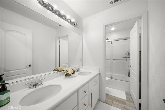 full bath featuring double vanity, combined bath / shower with glass door, a sink, and visible vents