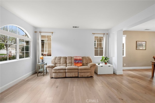 living area with light wood finished floors, visible vents, and baseboards