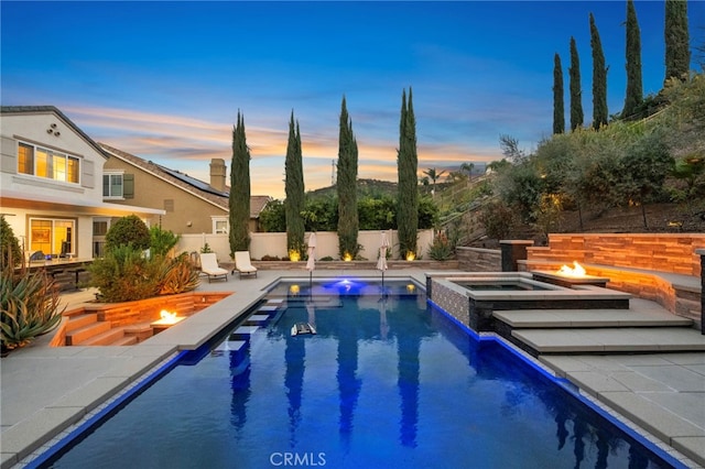 view of pool featuring an outdoor fire pit, a pool with connected hot tub, a fenced backyard, and a patio