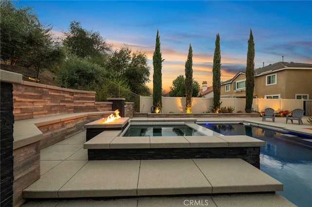 pool at dusk featuring a fenced in pool, an outdoor fire pit, a patio area, and a fenced backyard