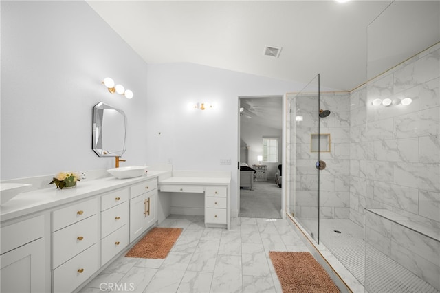 bathroom with connected bathroom, a sink, vaulted ceiling, marble finish floor, and a tile shower