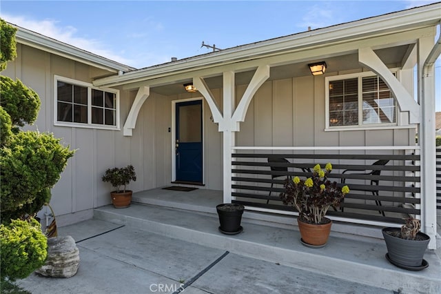 view of exterior entry featuring covered porch and board and batten siding