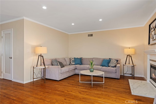 living area with a premium fireplace, ornamental molding, and wood finished floors