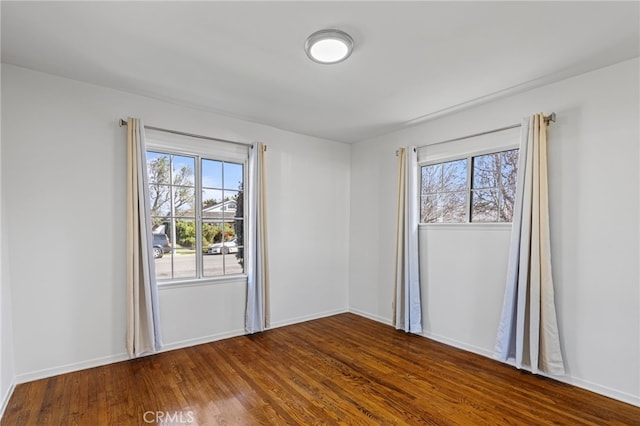 empty room with dark wood-style floors, baseboards, and a wealth of natural light