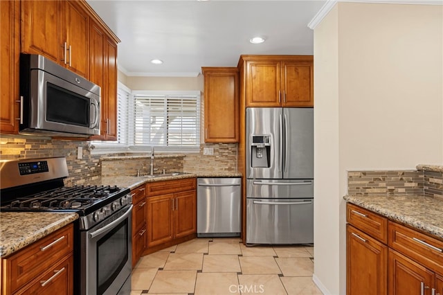 kitchen with crown molding, appliances with stainless steel finishes, brown cabinetry, and a sink