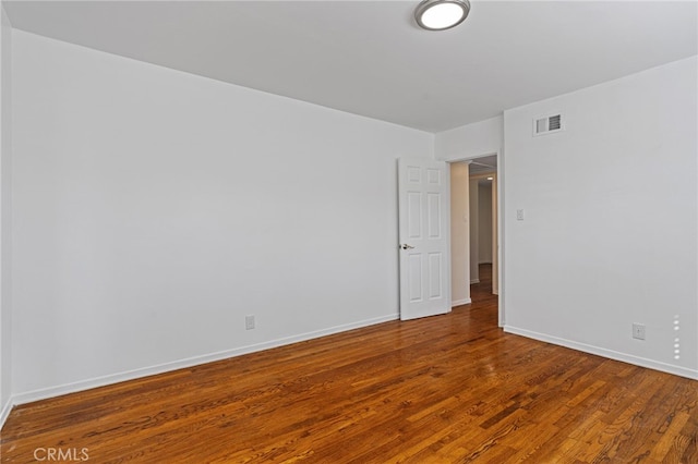 unfurnished room with wood finished floors, visible vents, and baseboards