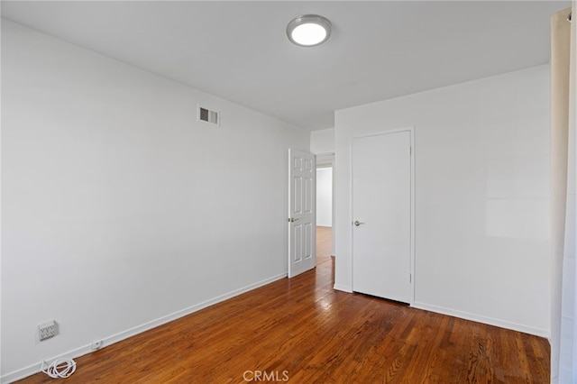 unfurnished bedroom featuring wood finished floors, visible vents, and baseboards