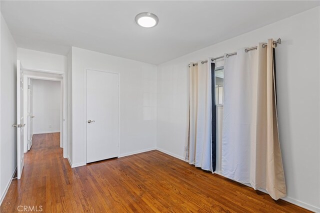 spare room with baseboards and wood finished floors