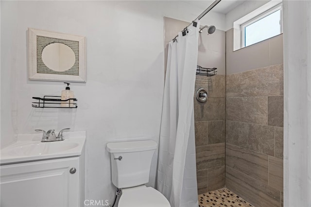 bathroom with tiled shower, vanity, and toilet