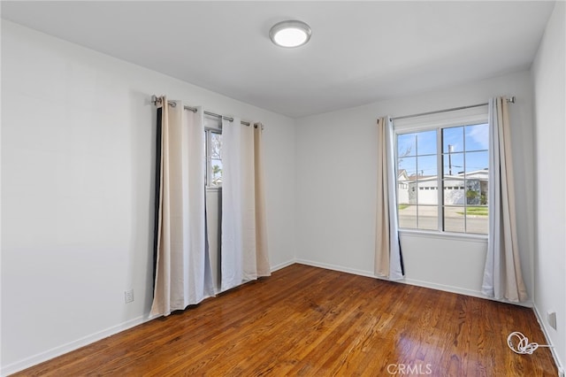 unfurnished room with baseboards, a wealth of natural light, and wood finished floors