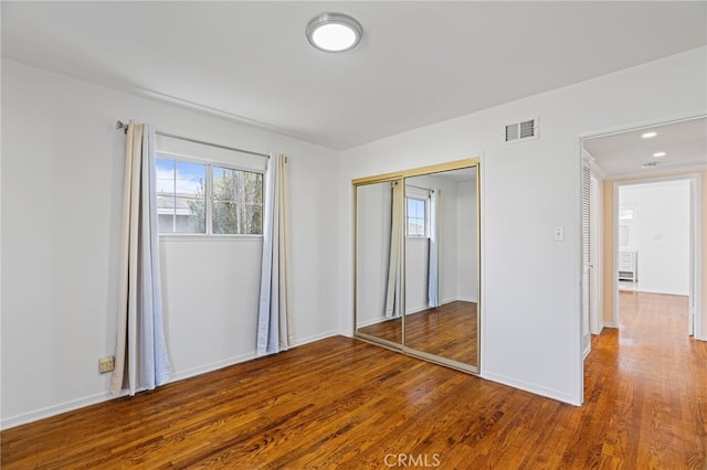 unfurnished bedroom featuring recessed lighting, wood finished floors, visible vents, baseboards, and a closet