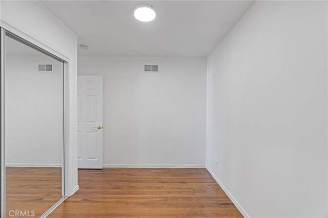 interior space featuring a closet, wood finished floors, visible vents, and baseboards