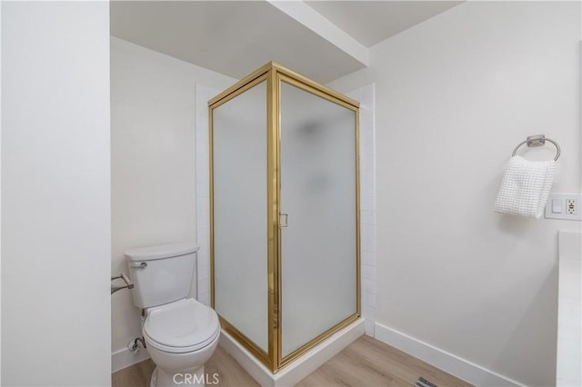 bathroom featuring a stall shower, baseboards, toilet, and wood finished floors