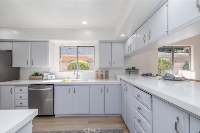 kitchen with recessed lighting, a sink, light wood-style floors, light countertops, and stainless steel dishwasher