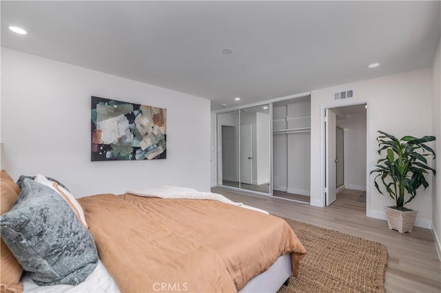 bedroom with light wood-style floors, recessed lighting, a closet, and visible vents