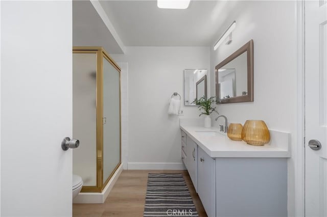 bathroom featuring a stall shower, baseboards, toilet, wood finished floors, and vanity