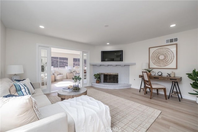 living room with light wood-style floors, a fireplace, visible vents, and recessed lighting