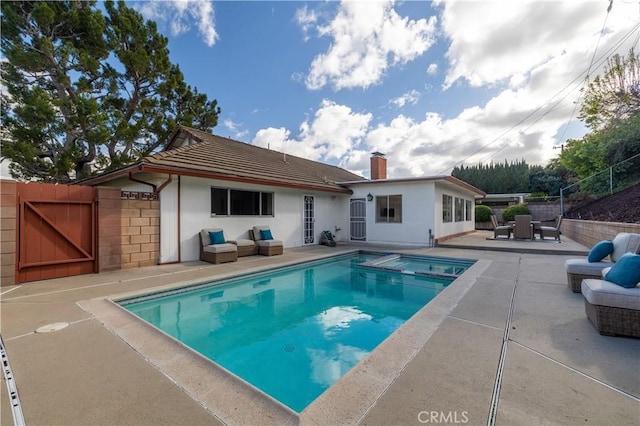 view of pool with outdoor lounge area, fence, a pool with connected hot tub, a gate, and a patio area