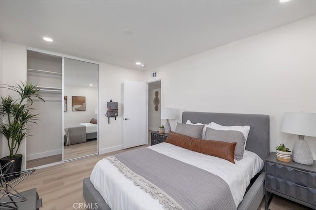 bedroom with light wood finished floors, recessed lighting, a closet, visible vents, and baseboards