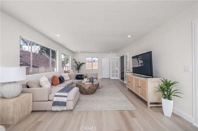 living room featuring light wood-type flooring, baseboards, and recessed lighting