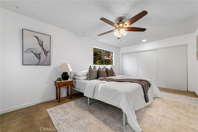 bedroom featuring a textured ceiling, a closet, carpet, and a ceiling fan