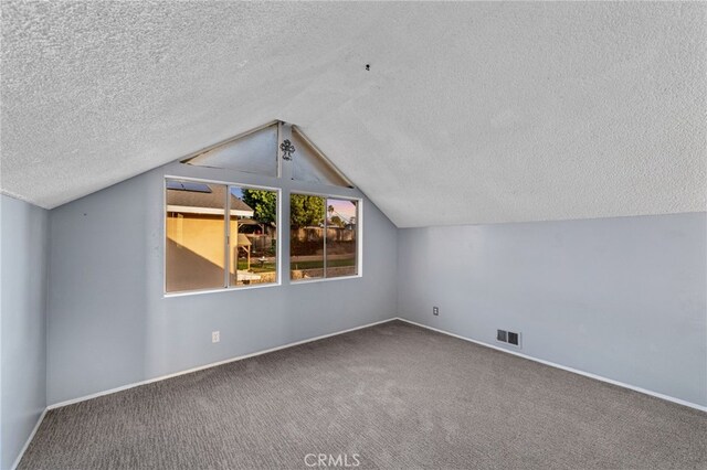 bonus room with carpet, lofted ceiling, visible vents, a textured ceiling, and baseboards