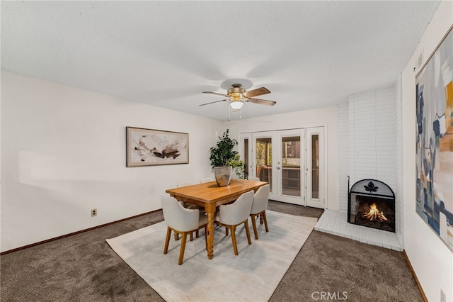 dining area featuring carpet floors, a fireplace, baseboards, and ceiling fan