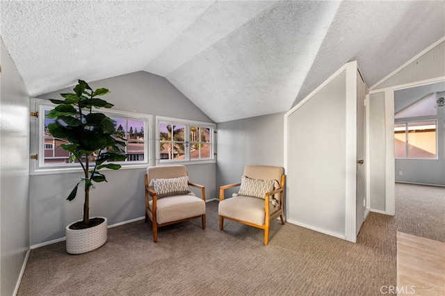 living area featuring carpet floors, baseboards, vaulted ceiling, and a textured ceiling