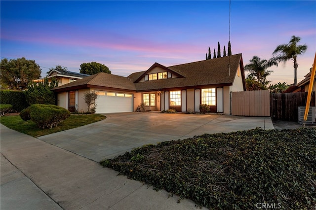 view of front of house with central AC, fence, an attached garage, and stucco siding