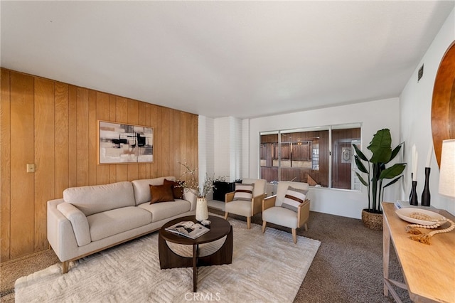 carpeted living room with wood walls and visible vents