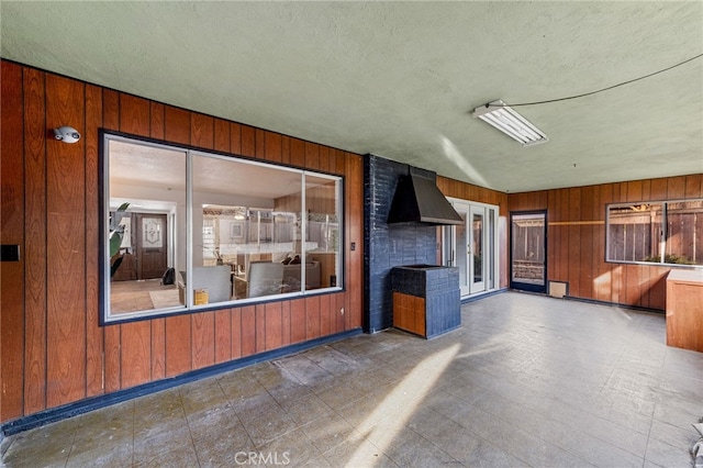 interior space with wooden walls, a textured ceiling, and tile patterned floors