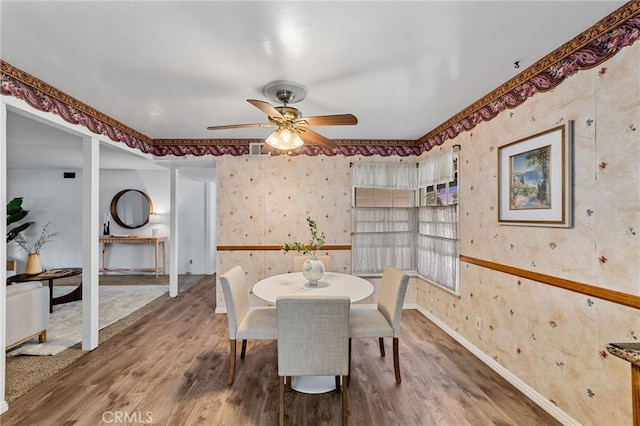 dining space featuring baseboards, wood finished floors, visible vents, and wallpapered walls