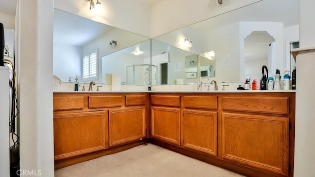 full bath with a shower with door, a sink, and double vanity