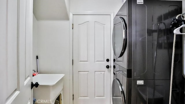 laundry room featuring stacked washer / drying machine, laundry area, and a sink