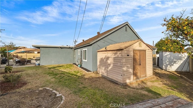 view of side of home with a storage shed, stucco siding, an outbuilding, a patio area, and a yard