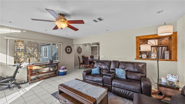 tiled living room featuring visible vents, baseboards, and ceiling fan
