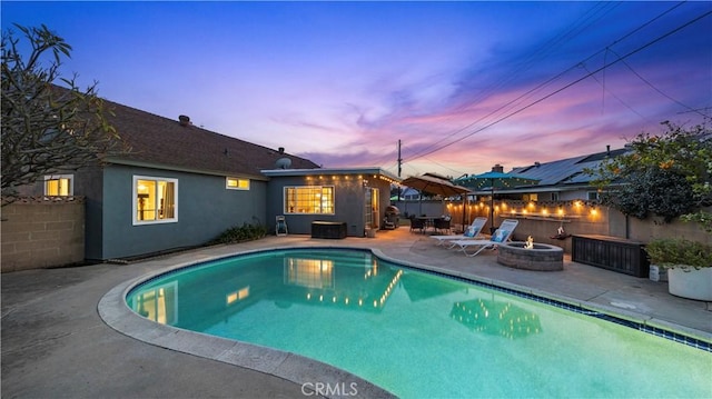 pool at dusk featuring a fenced in pool, a patio, a fire pit, and fence