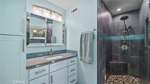 full bathroom featuring vanity, visible vents, and tiled shower