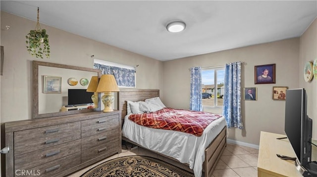 bedroom featuring light tile patterned floors, baseboards, and multiple windows