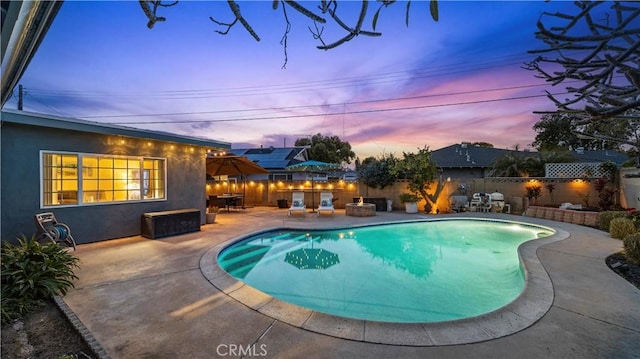 pool at dusk featuring a patio area, a fenced in pool, and a fenced backyard