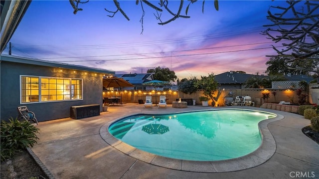 pool at dusk featuring a patio, a fenced in pool, and a fenced backyard