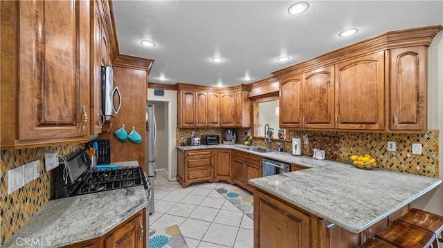 kitchen featuring brown cabinets, a sink, appliances with stainless steel finishes, a peninsula, and light tile patterned floors